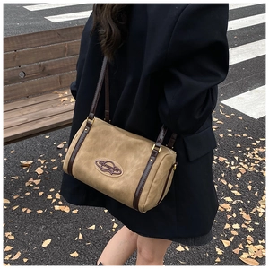 Detail of khaki suede Boston bag with brown leather straps in a fall street setting