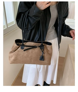 Detail of a large brown suede tote bag with black straps on a fashion model