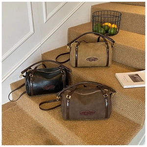 Three minimalist Boston shoulder bags in black, dark coffee, and khaki on a stylish staircase