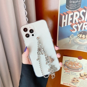 Detail of white phone case with silver metal chain and bear charms on retro background