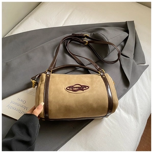 Close-up of khaki suede barrel bag with brown patent leather trim and gold hardware