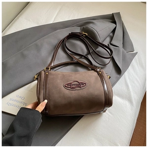 Close-up of matte suede Boston bag featuring dark brown leather trim and golden hardware