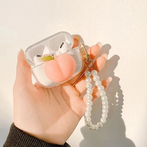Transparent AirPods case with 3D peach charm and white pearl wrist strap held by hand