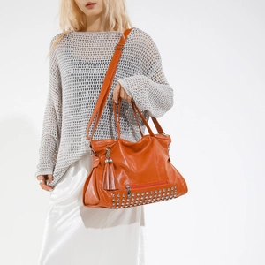 Orangefarbene Totebag aus Kunstleder mit Nieten und Fransen für den täglichen Pendelverkehr