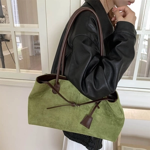 Vintage green suede tote bag with brown leather straps shown in a minimalist setting