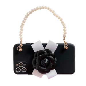Detail of black camellia flower and pearl handle on smartphone case with white bow