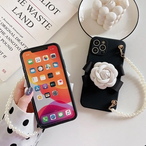 Detailed close-up of iPhone case featuring a white camellia flower and pearl lanyard