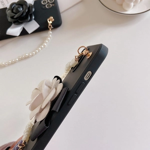Macro shot of 3D white camellia and velvet bow details on black phone case with pearl strap