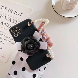 Detail of black iPhone case featuring 3D camellia flower and pearl wrist strap