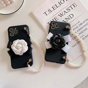 Detail of matte black phone case with camellia flower decor and pearl wrist strap