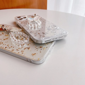 Detail of iPhone case with silver foil flakes, butterfly stand and gold leaf bead bracelet