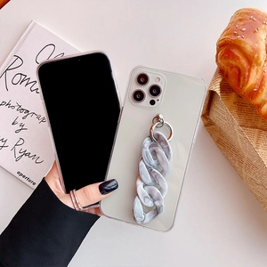 Detail of marble pattern chunky chain strap on a frosted cream phone case held by a model