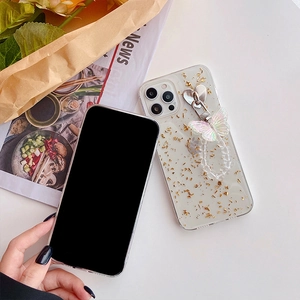 Detailed view of clear iPhone case with gold foil flakes and butterfly charm wrist strap