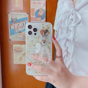 Close-up of gold foil iPhone case with heart ring, butterfly charm and beaded strap