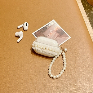 Detailed view of clear lace AirPods Pro case with pearl chain on brown leather