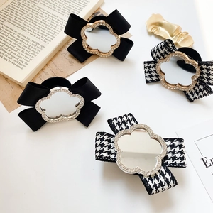Close-up of bow phone grips with sparkling crystal flower mirrors and houndstooth patterns