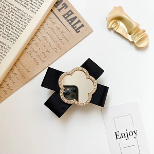 Close-up of bow phone stand with black ribbon, golden floral frame and center mirror