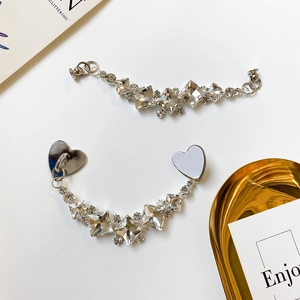 Detail of square crystal chain with silver heart accents on a luxury gold tray