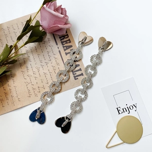 Detail of silver long tassel earrings with sparkling rhinestones and heart charms