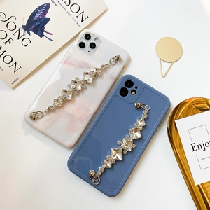 Detalle de cadena de muñeca con pedrería de lujo en fundas de mármol y azul mate