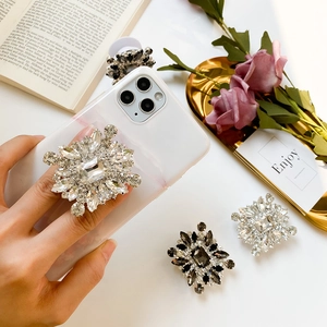 Macro detail of rhinestone pop socket phone grips featuring sparkling crystals on white table