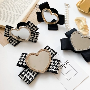 Close-up of heart mirror phone stand with rhinestones and black ribbon bow detail