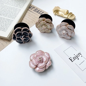 Detailed view of floral phone sockets with camellia design and pearl trim on white surface