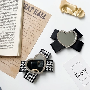 Macro shot of stylish bow phone stand with rhinestones and heart-shaped mirror detail
