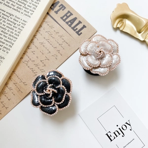 Macro detail of camellia flower phone stands with pearl edging and glossy finish