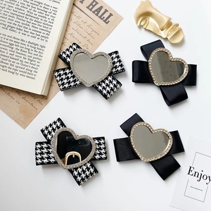 Detail of heart-shaped mirror bow phone stand with rhinestones in black and houndstooth