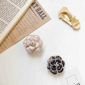 Macro detail of camellia resin clips with pearl edges and golden metal face hairpins