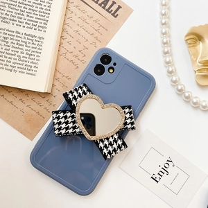 Macro shot of phone case with heart mirror stand and houndstooth bow tie ornament