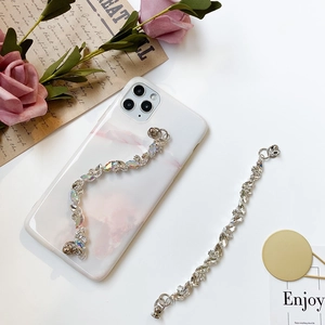 Detail view of marble phone case with sparkling rhinestone heart chain and floral accents