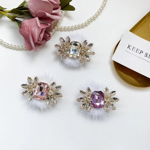 Close-up of sparkling rhinestone hair clips on soft white fur pompoms in three elegant colors