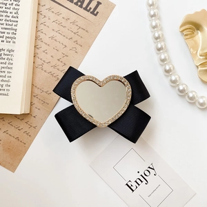 Detail of elegant bow phone stand with heart-shaped mirror and sparkling rhinestones