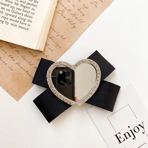 Detail of a black ribbon bow phone stand featuring a sparkling rhinestone heart mirror