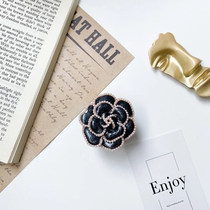 Detail view of retro camellia phone grip with white faux pearl trim and black finish