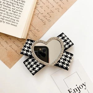 Detail of bow-shaped holder with houndstooth pattern and heart-shaped rhinestone mirror