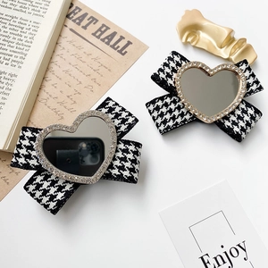 Detail of houndstooth bow hair clips with heart mirror and rhinestone on retro background