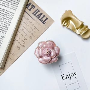 Close-up of pink camellia phone grip with pearl edges and shiny enamel texture