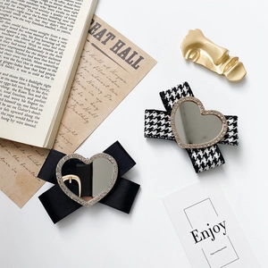 Detail shot of bow hair clips with heart mirrors and gold abstract face metal clip