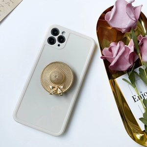 Detail shot of golden straw hat phone stand with woven texture and bow on cream phone case