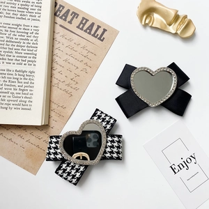 Detailed macro view of heart-shaped mirrors on bow hairpins with houndstooth fabric pattern