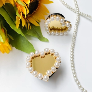 Close-up of heart-shaped phone grip with golden mirror and pearl border decoration