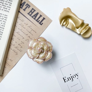 Detailed macro view of camellia phone grip with pearl edges and champagne gold finish