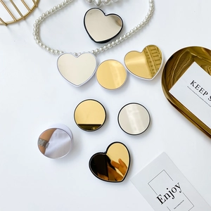 Close-up of heart and round mirror phone sockets in gold and silver finish on white surface