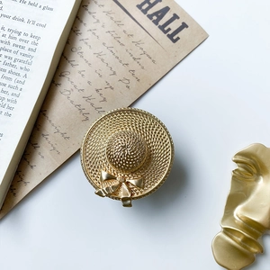 Close-up of golden straw hat accessory with metal texture and bow detail