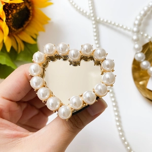 Close-up of heart-shaped phone grip with mirror surface and white pearl inlay