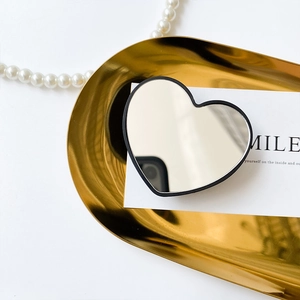 Macro shot of heart-shaped mirror phone stand on a golden tray with elegant accessories