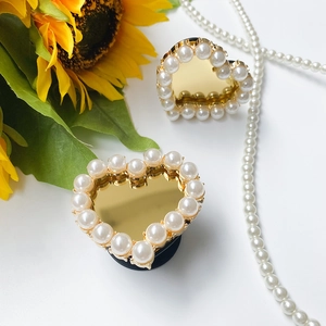 Detail of heart-shaped mirror phone stand with pearl trim and yellow sunflower decor
